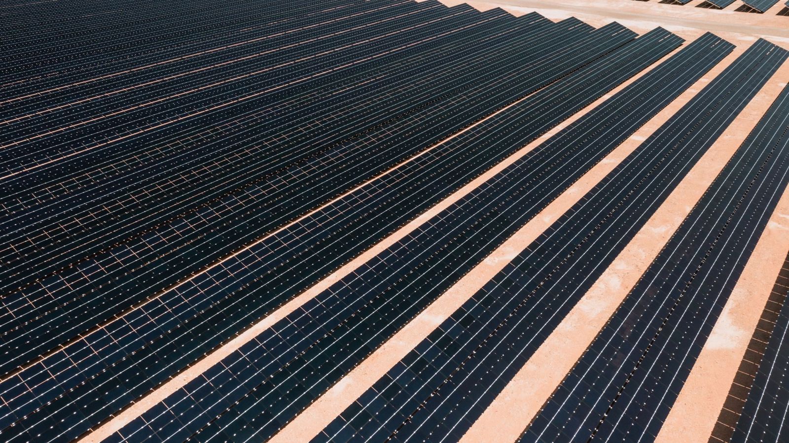 Luftbild eines Solarparks mit regelmäßigen Modulreihen